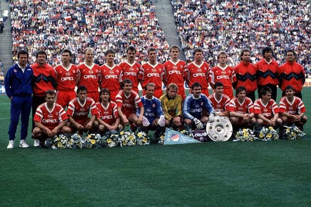 Die Bayern, Meister 1990: h.R.v.l.: Trainer Jupp Heynckes, Co-Trainer Egon Coordes, Klaus Augenthaler, Hans Pflügler, Roland Wohlfarth, Jürgen Kohler, Thomas Strunz, Manfred Bender, Stefan Reuter, Hans Dorfner, x, Arzt Dr. Hans-Wilhelm Müller-Wohlfahrt,x Fußball 1. BL Herren Saison 1989 1990, Bayern München, Meisterfeier, Landesmeister, Mannschaftsfoto, Mannschaftsbild Totale Olympiastadion München