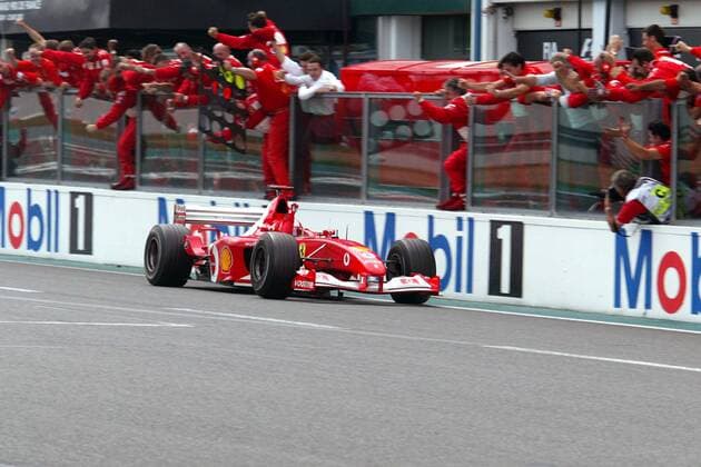 Der frischgebackene Weltmeister Michael Schumacher (Deutschland Ferrari) passiert in seinem Rennwagen seine jubelnde Boxencrew Motorsport Grand Prix Herren Großer Preis von Frankreich 2002, Formel 1 Weltmeisterschaft, F1, F, GP, WM, Vdig Totale Circuit de Nevers Magny-Cours Freude, Begeisterung,