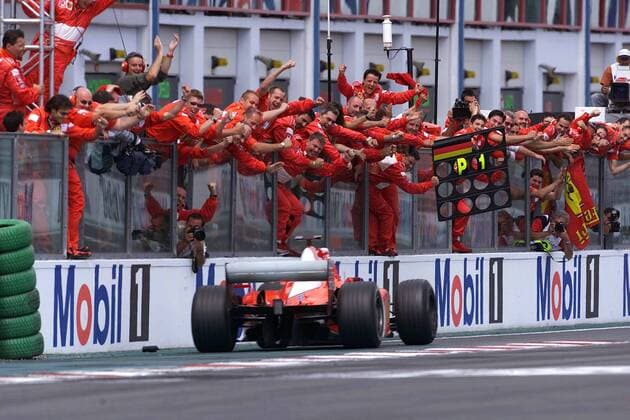 Weltmeister Michael Schumacher (Deutschland Ferrari) fährt in seinem Rennwagen an seiner jubelnden Boxencrew vorbei Motorsport Grand Prix Herren Großer Preis von Frankreich 2002, Formel 1 Weltmeisterschaft, F1, F, GP, WM, Vdig Totale Circuit de Nevers Magny-Cours Freude, Begeisterung