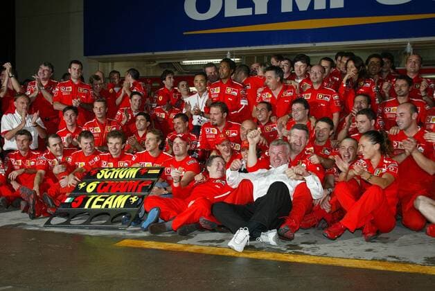Das gesamte Ferrari-Team um Michael Schumacher (Mitte), seinem Manager Willi Weber (vorn, beide Deutschland), Technikchef Ross Brawn (England, dahinter), Rubens Barrichello (6.v.li., Brasilien) und Teamchef Jean Todt (Frankreich, 7.v.li.) feiern die Titel Motorsport Grand Prix Herren Großer Preis von Japan 2003, Formel 1 Weltmeisterschaft, F1, F, GP, WM Totale Suzuka Freude, Begeisterung,