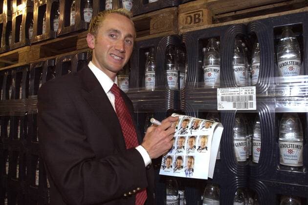 Davide Rebellin (Italien Team Gerolsteiner) unterschreibt vor einem Regal mit Gerolsteiner Mineralwasser einen Autogrammkarten-Bogen Radsport Herren Präsentation Team Gerolsteiner 2003, Vorstellung, Pressetermin, Straßenradsport, Rad, Straße Einzelbild Gerolstein