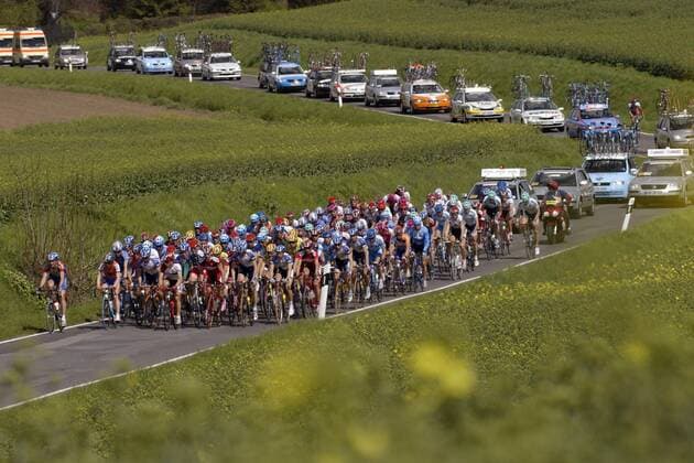 Grün ist die Heide: Das Teilnehmerfeld der 28. Niedersachsen-Rundfahrt, im Hintergrund der Tross der Begleitfahrzeuge Radsport Herren 28. Internationale Niedersachsen-Rundfahrt 2004, Straßenradsport, Straße, Rad Totale 1. Etappe: Wolfsburg - Duderstadt