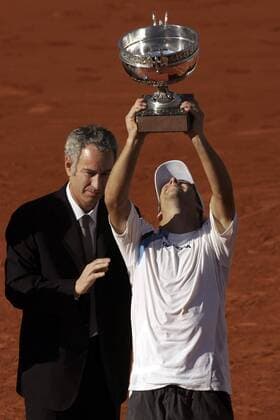 Gaston Gaudio (Argentinien) streckt triumphierend die Siegertrophäe der French Open 2004 in die Luft, li. applaudiert John McEnroe (USA) Tennis Herren French Open 2004, Grand Slam, ATP-Tour, Sand, Sandplatz, Sandplatztennis, Sandplatzturnier, Vdig, Gruppe Roland Garros Paris Begeisterung, Freude,