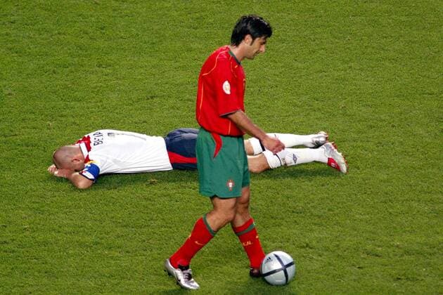 David Beckham (England) liegt verletzt am Boden, während Luis Figo (Portugal) gemütlich den Ball spazieren führt Fußball EM Herren Euro 2004, Europameisterschaft, Länderspiel, Nationalmannschaft, Nationalteam, Viertelfinale Gruppe Lissabon  