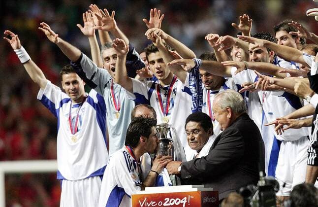 Kapitän Theodoros Zagorakis (vorn li., Griechenland) küßt den EM-Pokal, seine Teamkollegen jubeln hinter dem Rücken von UEFA-Präsident Lennart Johansson (vorn re., Schweden) und Eusebio (Mitte, Portugal), der betreten dreinschaut Fußball EM Herren Europameisterschaft, Euro 2004, Länderspiel, Nationalmannschaft, Nationalteam, Finale, Endspiel Totale Lissabon Glück, Begeisterung, Freude,