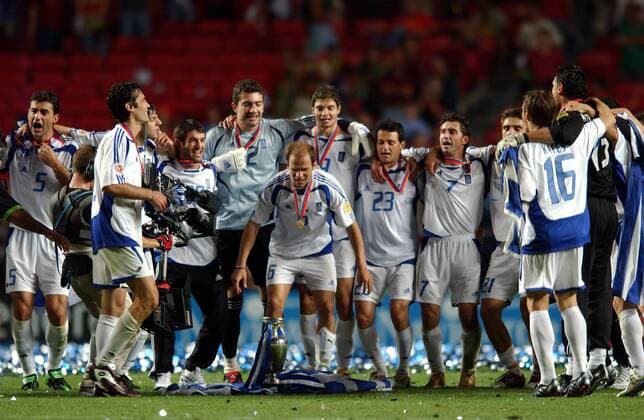 Fußball, EM Finale 2004 in Lissabon, Portugal - Griechenland 0:1 Angelos Basinas (vorn) legt eine Nationalfahne zum Europameister Pokal, hi.v.li.: Traianos Dellas, x, Panagiotis Fyssas, Georgios Karagounis, Torwart Kostas Chalkias, Angelos Charisteas, Vassilios Lakis, Theodoros Zagorakis (alle Griechenland) Fußball EM Herren Euro 2004, Europameisterschaft, Länderspiel, Nationalmannschaft, Nationalteam, Finale, Endspiel Gruppe Lissabon