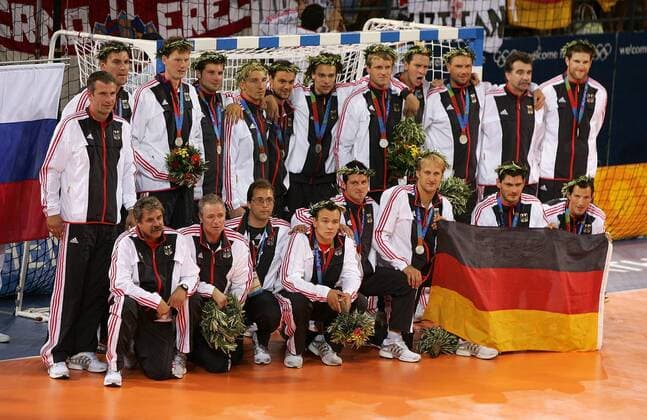 Deutschland gewinnt Silber hi.v.li.: Co-Trainer Frank Löhr, Mark Dragunski, Volker Zerbe, Daniel Stephan, Stefan Kretzschmar, Markus Baur, Frank von Behren, Klaus Dieter Petersen, Pascal Hens, Christian Schwarzer, Bundestrainer Heiner Brand, ... Handball OS Sommer Herren Olympische Sommerspiele Athen 2004, Olympia, Olympiade, Spiele, Nationalmannschaft, Nationalteam, Totale Mannschaftsfoto, Mannschaftsbild Helliniko