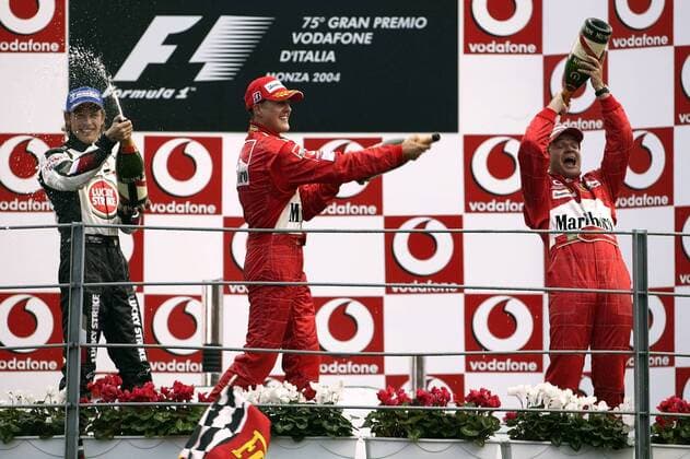 Siegerehrung nach dem GP von Italien in Monza 2004, v.li.: Jenson Button (England BAR-Honda), Michael Schumacher (Deutschland) und Sieger Rubens Barrichello (Brasilien beide Ferrari) bei der Sektdusche Motorsport Grand Prix Herren Großer Preis von Italien 2004, Formel 1 Weltmeisterschaft, F1, F, GP, WM Gruppe Autodromo Nazionale Monza Begeisterung, Freude,