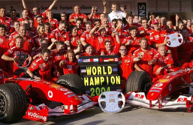 Nach dem GP von Ungarn in Budapest 2004 feiern Michael Schumacher (Deutschland, 3.v.re.), Rubens Barrichello (Brasilien, li.) und Teamchef Jean Todt (Frankreich, Mitte) im Kreise der Scuderia Ferrari den Gewinn der Konstrukteursweltmeisterschaft Motorsport Grand Prix Herren Großer Preis von Ungarn 2004, Formel 1 Weltmeisterschaft, F1, F, GP, WM, Weltmeister Totale Hungaroring, Teamwertung, Teamfoto Budapest, Konstrukteurswertung, Sieg, Sieger Begeisterung, Freude,