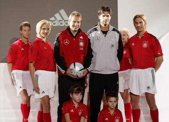 Bundestrainer Jürgen Klinsmann (li.) und Michael Ballack (beide Deutschland) stellen gemeinsam mit jungen Models die neuen Trikots der Nationalmannschaft von adidas vor - rot wurde gewählt um Aggressivität auszustrahlen Fußball Herren Nationalmannschaft 2004, Nationalteam, Vorstellung, Präsentation, Pressetermin, Vdig Gruppe Kommerzialisierung Leipzig, Auswärtstrikot