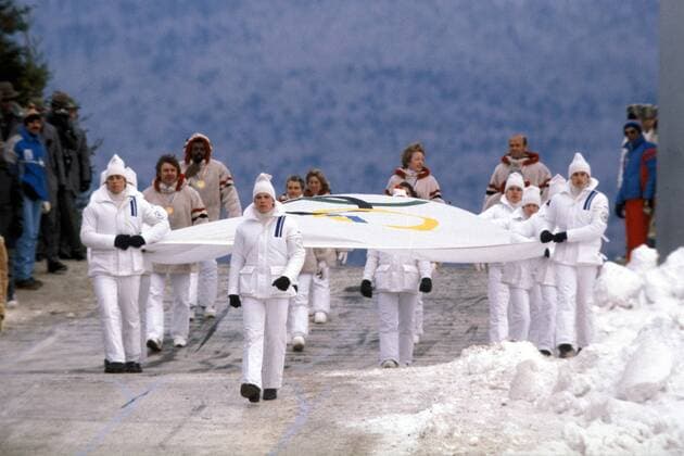 Eröffnungszeremonie der Olympischen Spiele 1980 in Lake Placid - Ehemalige Olympiasieger der USA, darunter Eisschnelläufer Jack Shea, Diskuswerfer Al Oerter und Boxer Floyd Patterson, begleiten die Olympiafahne auf ihrem Weg ins Stadion Eisschnellauf OS Winter Herren Olympische Winterspiele 1980, Olympia, Olympiade, Spiele, Eröffnung, Eröffnungsfeier, Feier, Vdia Totale Lake Placid