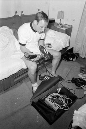 Do it yourself: Uwe Seeler (BR Deutschland) schraubt im Hotelzimmer seine Stollen fest Fußball WM Herren Weltmeisterschaft 1966, Nationalmannschaft, Nationalteam, BRD Einzelbild Ausrüstung, Equipment, Adidas, Ausrüster anschrauben, festschrauben