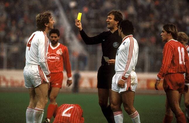 Schiedsrichter Siegfried Brehm zeigt Ditmar Jakobs (li.) die Gelbe Karte, daneben Felix Magath (beide HSV) und Olaf Janßen Fußball 1. BL Herren DEUTSCHSPRACHIGE SPORTZEITSCHRIFTEN UND -ZEITUNGEN NUR NACH RÜCKSPRACHE, Saison 1985 1986 Gruppe Hamburg Dynamik,