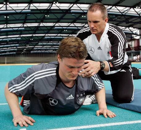 Robert Huth (li., Deutschland) und Trainingsberater Mark Verstegen (USA Athletes Performance) arbeiten an der Beweglichkeit des Spielers Fußball Herren Nationalmannschaft 2005, Nationalteam, Training, Vorbereitung, Trainingswissenschaft, Vdig Gruppe Fitneß, Fitness, Fitneßtraining, Fitnesstraining Frankfurt M., Fitneßcoach, Fitnesscoach
