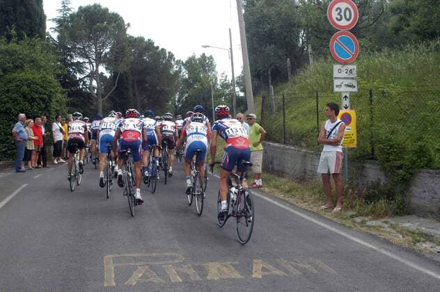 Das Feld des Memorial Pantani Rennens auf einer Straße unterwegs, die mit dem Namenszug des früh verstorbenen Radprofis Marco Pantani (Italien) gezeichnet ist -  Radsport Herren Memorial Pantani 2005, Straßenradsport, Straße, Rad, Erinnerungsrennen, Erinnerung, erinnern Totale