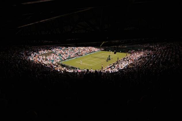 Volle Ränge auf dem Centre Court in Wimbledon - während die Zuschauer im Schatten sitzen, gehen die Spieler auf dem sonnenüberfluteten Platz ihrer Arbeit nach Tennis Herren All England Championships 2005, Grand Slam, ATP Tour, Rasen, Rasenplatz, Rasentennis, Rasenturnier Totale Wimbledon, Perspektive, Zuschauerperspektive London