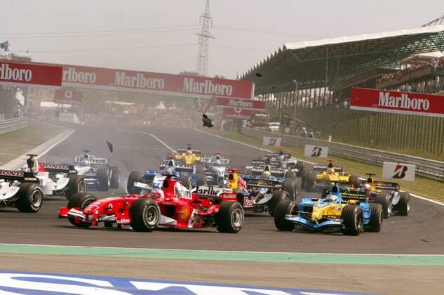 Start zum GP von Ungarn 2005: Bereits in der ersten Kurve muss sich der hintere Teil des Fahrerfeldes mit herumfliegenden Fahrzeugteilen auseinandersetzen, vorn: Rubens Barrichello (Brasilien Ferrari) und Giancarlo Fisichella (Italien Renault) Motorsport Grand Prix Herren Großer Preis von Ungarn 2005, Formel 1 Weltmeisterschaft, F1, F, GP, WM Totale Hungaroring Budapest