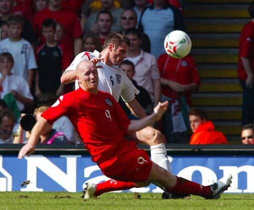 John Hartson (Wales, vorn) gegen Jamie Carragher (England) -  Fußball Länderspiel Herren Weltmeisterschaftsqualifikation 2005, Nationalmannschaft, Nationalteam, Nationaltrikot, Länderspiel Gruppe Cardiff Dynamik, Kampf,