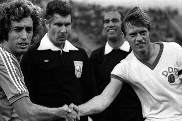 Enrique Ernesto Wolff (Argentinien, li.) und Bernd Bransch (DDR, re.) bei der Begrüßung, dahinter schauen Schiedsrichter John Taylor (England, 2.v.li.) und Linienrichter Mustafa Kamel (Ägypten) zu Fußball WM Herren Weltmeisterschaft 1974, Nationalmannschaft, Nationalteam, Nationaltrikot, Länderspiel, Zwischenrunde Gruppe Gelsenkirchen Harmonie,