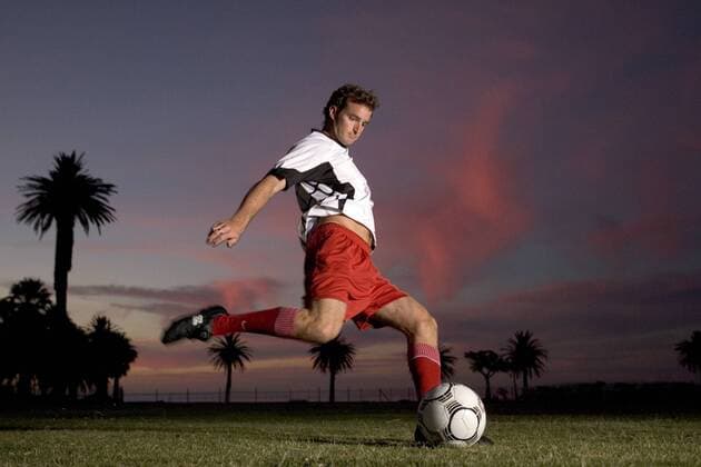 Fußballspieler beim Torschuß vor abendlichem Himmel und Palmen - MODEL RELEASED Fußball Herren Freizeitfußball 2005, Symbol, Feature, Aufmacher, Freizeitsport, Freizeitsportler, Fußballspieler Einzelbild Dynamik,