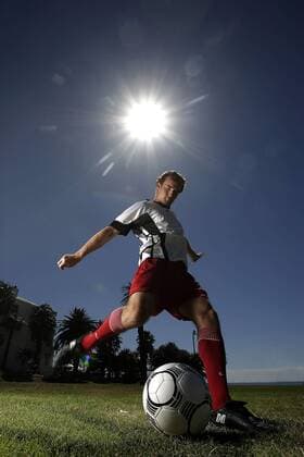 Fußballspieler beim Torschuß unter Sonnenschein - MODEL RELEASED Fußball Herren Freizeitfußball 2005, Symbol, Feature, Aufmacher, Freizeitsport, Freizeitsportler, Fußballspieler Einzelbild Ausrüstung, Equipment Dynamik,