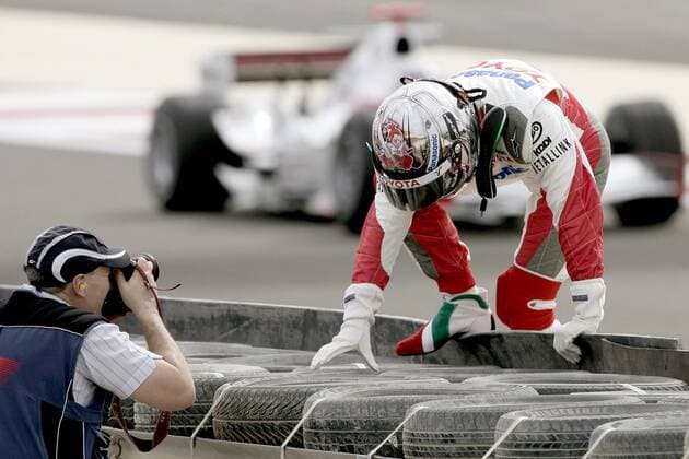 Jarno Trulli (Italien Toyota) steigt nach seinem Ausfall über die Absperrung, ein Fotograf findet sein Motiv Motorsport Grand Prix Herren Großer Preis von Bahrain 2006, Formel 1 Weltmeisterschaft, F1, F, GP, WM, Freies Training Gruppe Bahrain International Circuit Manama, Sakhir