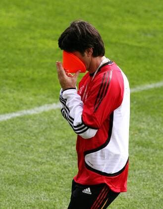 Co Trainer Joachim Löw (Deutschland) versteckt sein Gesicht in einem Hütchen Fußball WM Herren Nationalmannschaft 2006, Nationalteam, Vorbereitung, Training Einzelbild Genf Komik,