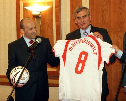 Nationaltrainer Pawel Janas (re.) beschenkt Premierminister Kazimierz Marcinkiewicz (beide Polen) vor der Abreise zur FIFA Weltmeisterschaft 2006 ein Nationaltrikot mit der Nr. 8 und dessen Namenszug -  Fußball WM Herren Vorschau Weltmeisterschaft 2006, Abschied, Verabschiedung, verabschieden, Abreise, Gruppe Warschau Freude,