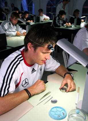 Sebastian Kehl (Deutschland) begutachtet seine Arbeit an einem Uhrwerk, das er vorher selbst auseinader- und wieder zusammengebaut hat - mit dieser Übung soll das Selbstvertrauen der Nationalspieler gestärkt werden Fußball WM Herren Nationalmannschaft 2006, Nationalteam, Trainingslager, Sponsorentermin, Ausflug Einzelbild Genf