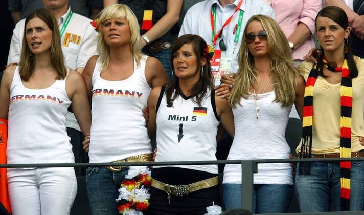 Die deutschen Spielerfrauen Arm in Arm während der Hymne, v.li.: Conny Lehmann, Ehefrau von Torwart Jens Lehmann, Natalie (Marcell Jansen), Tina (Sebastian Kehl), Monika (Lukas Podolski) mit Dior-Sonnenbrille und Sylwia Klose Fußball WM Herren WM 2006, Länderspiel, Nationalteam, Gruppe A, Gast, Gäste, Besucher, Publikum, Nationalfarben, quer Gruppe schwanger, Schwangerschaft, Schriftzug, Mini 5 Berlin, Deutschland Tribüne Fußball WM Herren WM 2006, Länderspiel, Nationalteam, Gruppe A, Gast, Gäste, Besucher, Publikum, Nationalfarben, quer Gruppe schwanger, Schwangerschaft, Schriftzug, Mini 5 Berlin, Deutschland Tribüne