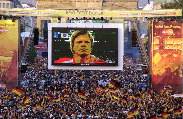 Deutsche Fans schwenken auf der Berliner Fanmeile ihre Landesfahnen während der Nationalhymne - Auf der Großleinwand Torwart Oliver Kahn (Deutschland) Fußball WM Herren WM 2006, Länderspiel, Nationalteam, Spiel um Platz 3, drei, Fanfest, Fan Fest, Party, FIFA Fanmeile Totale Straße des 17. Juni, Brandenburger Tor Berlin Fußball WM Herren WM 2006, Länderspiel, Nationalteam, Spiel um Platz 3, drei, Fanfest, Fan Fest, Party, FIFA Fanmeile Totale Straße des 17. Juni, Brandenburger Tor Berlin