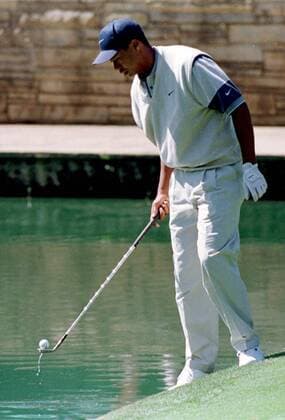 Eldrick Tiger Woods (USA) hat während des Trainings einen Ball im Wasser versenkt und holt ihn mit seinem Schläger wieder heraus -  (AUG97040803) Golf Herren Masters Tournament 1997, PGA Tour, Training Einzelbild Augusta Golf Herren Masters Tournament 1997, PGA Tour, Training Einzelbild Augusta