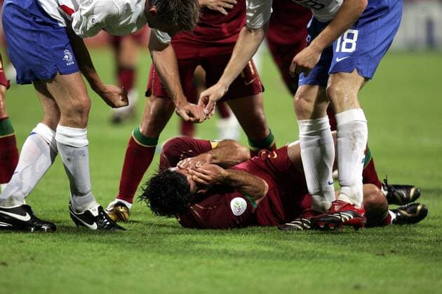 Luis Figo (Portugal, Mitte) wälzt sich verletzt auf dem Boden, Andre Ooijer (li.) und M. van Bommel (beide Niederlande) bezichtigen ihn der Schauspielerei und provozieren weiter -  Fußball Länderspiel Herren WM 2006, Nationalmannschaft, Nationaltrikot, Achtelfinale, Portugal - Niederlande 1:0 Gruppe Nürnberg Fußball Länderspiel Herren WM 2006, Nationalmannschaft, Nationaltrikot, Achtelfinale, Portugal - Niederlande 1:0 Gruppe Nürnberg
