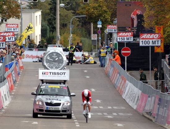 Hanka Kupfernagel (Deutschland) auf der Zielgeraden gefolgt von einem Auto mit überdimensionaler Armbanduhr auf dem Dach Radsport WM Damen WM 2007, Straßenradsport, Straße, Rad, Nationaltrikot, Zeitfahren Totale Zeit Uhrzeit Uhr überdimensional groß übergroß Stuttgart riesig Wagen Radsport WM Damen WM 2007, Straßenradsport, Straße, Rad, Nationaltrikot, Zeitfahren Totale Zeit Uhrzeit Uhr überdimensional groß übergroß Stuttgart riesig Wagen
