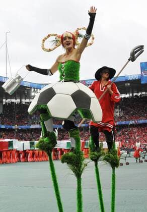 Artistin auf Stelzen im Fußball Outfit und ein Mann mit einer Forke während der Eröffnungsfeier der Euro 2008 Fußball EM Herren Euro 2008, Eröffnungsfeier, Eröffnung, Feier, Zeremonie Gruppe Basel Fußball EM Herren Euro 2008, Eröffnungsfeier, Eröffnung, Feier, Zeremonie Gruppe Basel