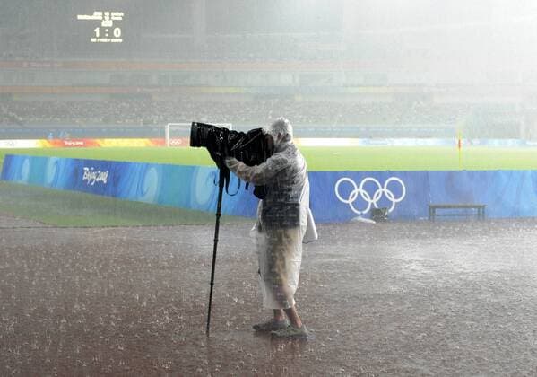Sportfotograf trotzt dem Regen - extreme Witterungsbedingungen führen zum zeitweiligen Spielabbruch beim in Shanghai ausgetragenen Viertelfinale der Olympischen Spiele - Fußball OS Sommer Damen Olympische Spiele Beijing 2008, Sommerspiele, Länderspiel, Nationalteam Viertelfinale Einzelbild Frauen, Frauenfußball Shanghai