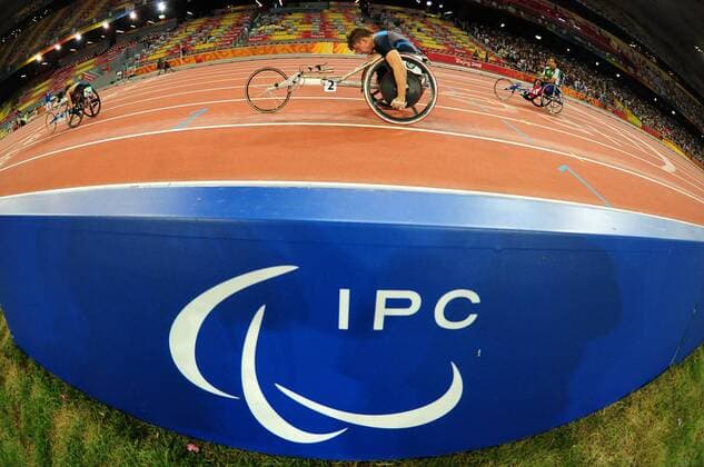 Rollstuhlfahrer passiert eine Bande mit dem Logo des IPC, des Internationalen Paralympischen Komitees -  Behindertensport Herren Paralympics 2008, Sommerspiele, Sommer Spiele, Behinderung, Rollstuhl, Leichtathletik, Einzelbild Peking