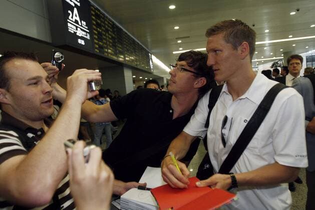 Bastian Schweinsteiger (Deutschland, re.) gibt nach seiner Ankunft auf dem Flughafen in Shanghai Autogramme -  (CFP399293249) Fußball Herren Nationalmannschaft 2009, o0 Asienreise Gruppe Shanghai