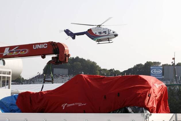Timo Glock (Deutschland Toyota) wird mit einem Rettungshubschrauber weggeflogen darunter sein zugedeckter zerstörter toyota