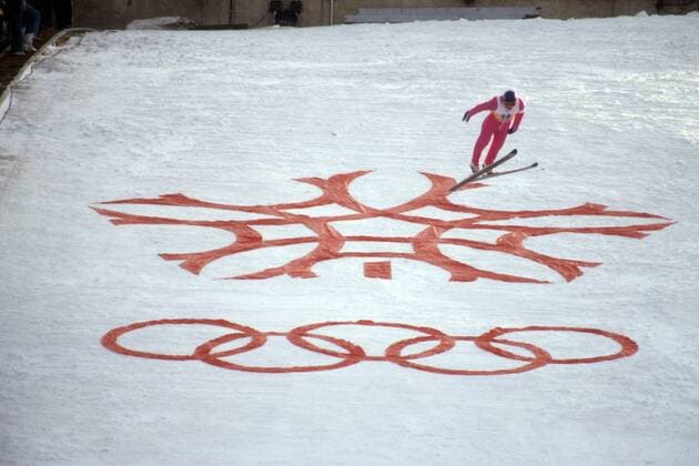 Skispringer während der Olympischen Spiele 1988 oberhalb des Logos der Spiele von Calgary Skispringen OS Winter Herren Olympische Spiele 1988, Winterspiele, Ski Nordisch, Skisport Totale Calgary