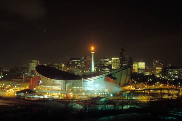 Olympisches Feuer auf dem Calgary Tower oberhalb des Olympic Saddledome vor der Skyline Calgarys, Austragungsort der Olympischen Spiele 1988 Eishockey OS Winter Damen Olympische Spiele Calgary 1988, Winterspiele Totale Calgary