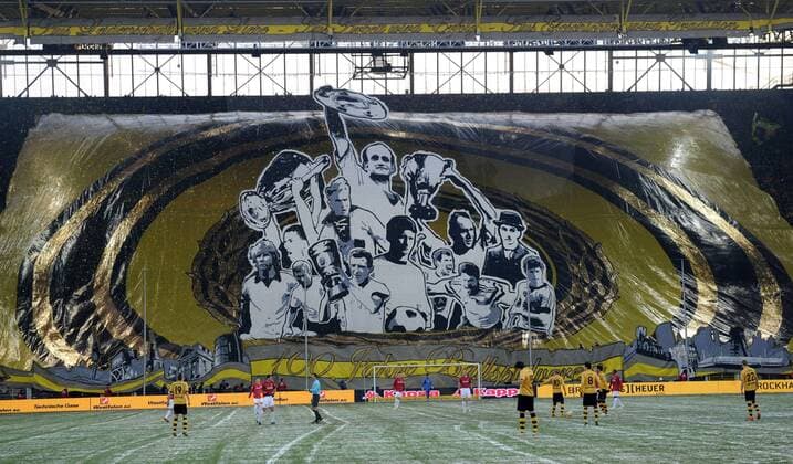 Fans auf der Südtribüne präsentieren zum hundertjährigen Vereinsjubiläum eine Riesenfahne mit den Konterfeis der BVB Vereinslegenden - oben: Alfred Adi Preißler mit der Meisterschale (1955-1956); Mitte v.li.: Lars Ricken mit dem Champions League Pokal (1996-1997), August Lenz, Wolfgang Paul mit dem Europapokal der Pokalsieger (1965-1966), Ehrenpräsident Franz Jacobi; unten: Manfred Burgsmüller, Sigfried Siggi Held, Alfred Aki Schmidt mit dem DFB Pokal (1964-1965), Jürgen Charly Schütz, Lothar Emmerich, Norbert Dickel, Michael Zorc o0 Plakat Transparent riesig Jubiläum hundert 100 Jahre Vereinsjubiläum