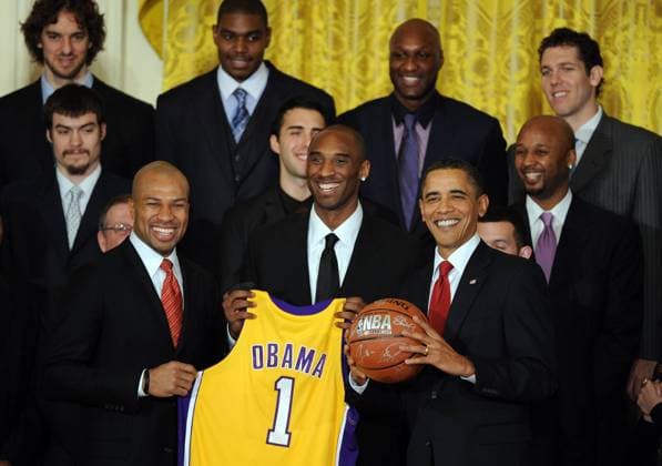 U.S. President Barack Obama receives a team jersey and autographed basketball from guards Derek Fisher (L) and Kobe Bryant (C) as Obama hosts the 2009 National Basketball Association Champion Los Angeles Lakers in the East Room of the White House in Washington on January 25, 2010.  WAP20100112509
