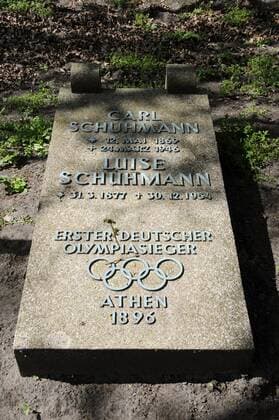 Gedenkstein für den ersten Deutschen Olympiasieger in einer Einzeldisziplin, Carl Schuhmann, bei den ersten Olympischen Spielen der Neuzeit 1896 in Athen. auf dem Gelände des Olympischen Dorfes von 1936 in Elstal (Havelland). Er gewann die Goldmedaille im Pferdsprung. Die ehemalige Grabplatte ist ein Geschenk seines Enkels an die Besucher des Olympischen Dorfes. o0 Objekte Turnen Geräteturnen Sieg Herren Partnerin, Frau, Ehefrau Luise