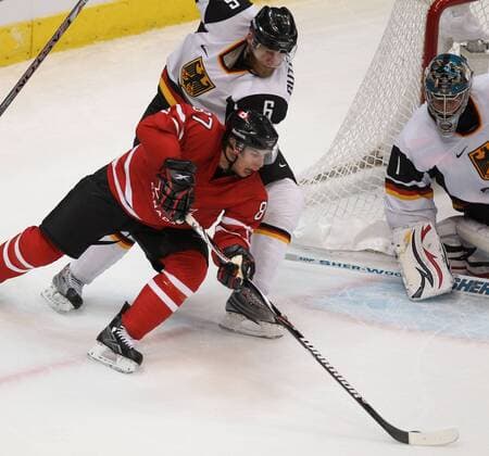 Canada s Sidney Crosby (L) shoots a backhand on german goalie Thomas Greiss (R) while being pressured by defenceman Sven Butenschön during second period of men s hockey game in Vancouver BC Tuesday, February 23, 2010 during the Winter Olympics. - ZUMAw51