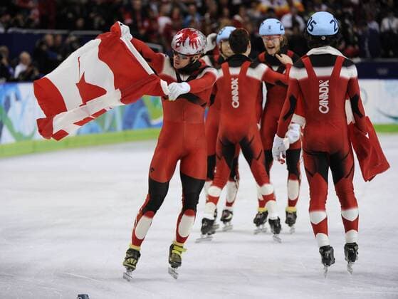Canadian skater Francois-Louis Tremblay (L) waves the Canadian flag as his team mates celebrate their goldmedals for the men s 5000 M relay short track speed skating - - ZUMAw51 o0 Objekte Flagge Nationalflagge o0 Jubel Freude Sieg Olympiasieg