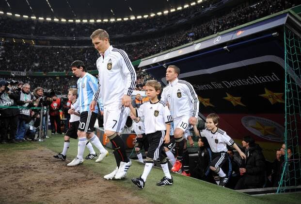 Deutschland - Argentinien 03.03.2010 Lionel Messi (li., ARG) mit Bastian Schweinsteiger, Lukas Podolski laufen ins Stadion ein (v. li., GER)  o00 DFB