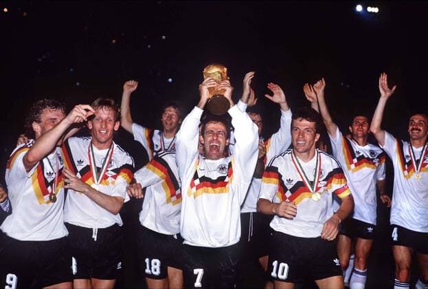 IMAGO Iconic Moments, Fußball Pierre Littbarski holds up the trophy (GER) Lothar Matthaeus (right), Rudi Voeller (left), Andreas Brehme (2nd left) Argentina v West Germany. World Cup Final 1990. Rome. 8 7 90.  o0 Siegerehrung o0 BRD BR