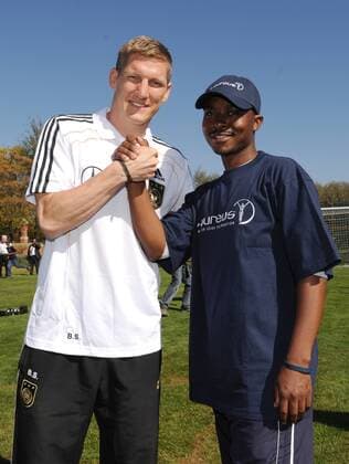 Nationalspieler Bastian SCHWEINSTEIGER (links, Deutschland) begruesst einen jungen Fussballer aus dem Laureus Profekt Sports for all aus Johannesburg. Laureus meets Nationalmannschaft -Kindertraining. Training der Deutschen Fussball Nationalmannschaft in Erasmia Centurion, 09.06.2010. FIFA - Fussball Weltmeisterschaft 2010 in Suedafrika