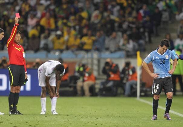 Nicolas Lodeiro (R) of Uruguay leaves the pitch after being given the red card by referee Yuichi Nishimura (L) during a Group match of the 2010 FIFA World Cup between Uruguay and France in Cape Town, on June 11, 2010. The match ended with a 0-0 draw. - France (white) vs Uruguay - 